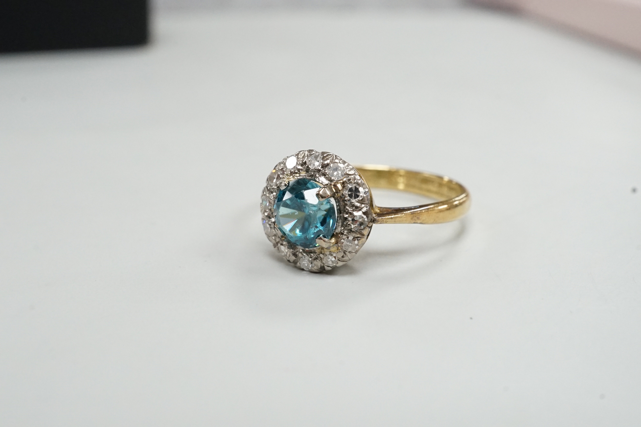 An 18ct & plat, blue zircon and illusion set diamond chip circular cluster ring, size M, gross weight 2.7 grams.